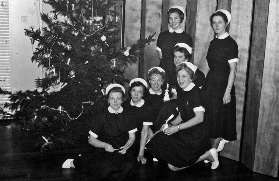 Black and white image of a group of nurses in front of a Christmas tree.